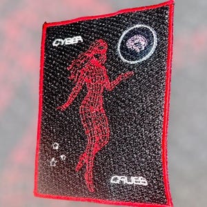 May include: Black patch with red trim featuring a red wireframe figure and the word "CYBER" at the top. A brain graphic is in a circle at the top right. The word "GALES" is at the bottom.