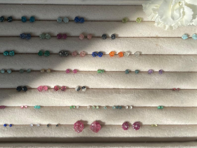 a white flower sitting next to a row of earrings
