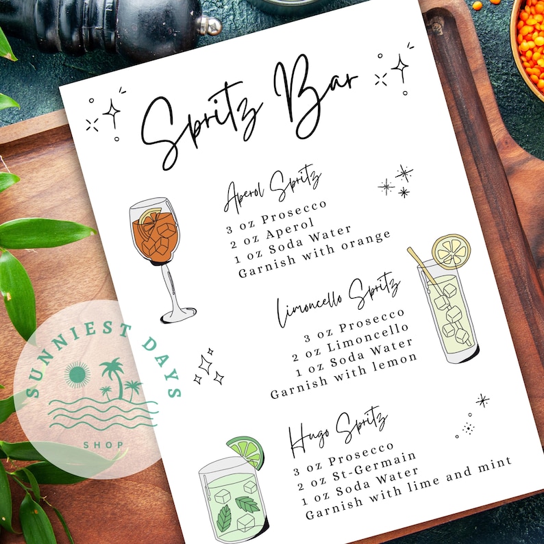 Peut inclure: Une affiche blanche imprim&eacute;e avec le texte "Spritz Bar" en &eacute;criture &eacute;l&eacute;gante. L'affiche pr&eacute;sente des illustrations et des recettes de cocktails Aperol, Limoncello et Hugo Spritz, avec ingr&eacute;dients et garnitures. L'affiche est sur une surface en bois.