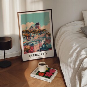 May include: A vintage-style poster with a colorful illustration of the cityscape of Quebec City, Canada. The poster is framed and hanging on a white wall above a bed with white linens.