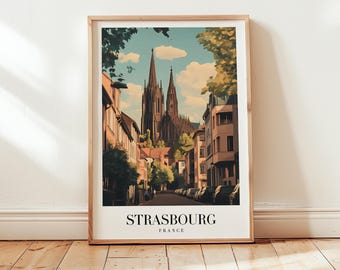 May include: A framed art print featuring a stylized illustration of Strasbourg, France. The artwork depicts a street scene with buildings, trees, and a cathedral in the background. The text "STRASBOURG FRANCE" is at the bottom.