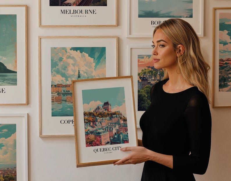 May include: A woman holds a framed print of a city skyline with the text "QUEBEC CITY CANADA". The print is surrounded by other framed prints of cityscapes.