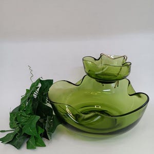 May include: A two-tiered green glass serving dish with a gold metal stand. The dish has a wavy edge and is ideal for serving snacks or dips.