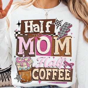 Könnte beinhalten: Weißes Sweatshirt mit dem Text "Half Mom Half Coffee" in einem mehrschichtigen Design. Das Design umfasst eine Kaffeetassen-Grafik, eine Schleife und ein Schachbrettmuster. Das Sweatshirt ist ein lässiger Stil.