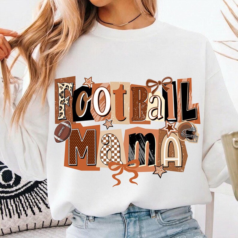 May include: White sweatshirt with the words "Football Mama" in a collage style. The letters are in shades of brown, black, and white, with football-themed accents like a football, helmet, and stars. The design includes bows.