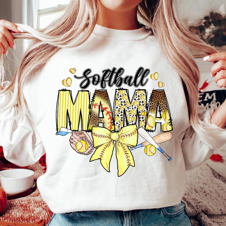 May include: White sweatshirt with the text "Softball Mama" in yellow and black letters with a yellow and black bow, baseball bats, and baseballs.