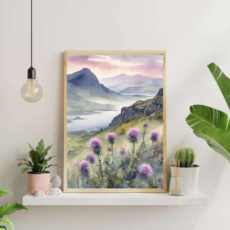 以下が含まれることがあります： 水彩画は、前景に紫色のアザミの花畑、背景に湖と山々を望む風景を描いています。空は淡いピンクと紫です。
