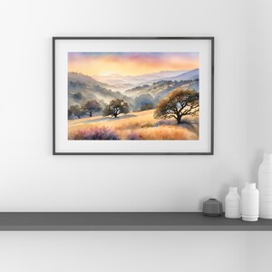May include: A watercolor painting of a landscape with rolling hills, trees, and a sunset sky. The colors are soft and muted, with shades of blue, purple, orange, and yellow. The painting is framed in a black frame.