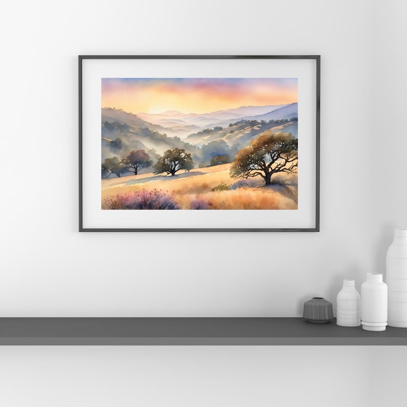 May include: A watercolor painting of a landscape with rolling hills, trees, and a sunset sky. The colors are soft and muted, with shades of blue, purple, orange, and yellow. The painting is framed in a black frame.