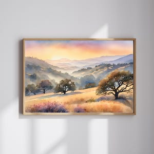 May include: A watercolor painting of a landscape with rolling hills, trees, and a sunset in the background. The sky is a mix of orange, pink, and purple. The hills are a soft green and brown. The trees are a dark green. The painting is framed in a light wood frame.