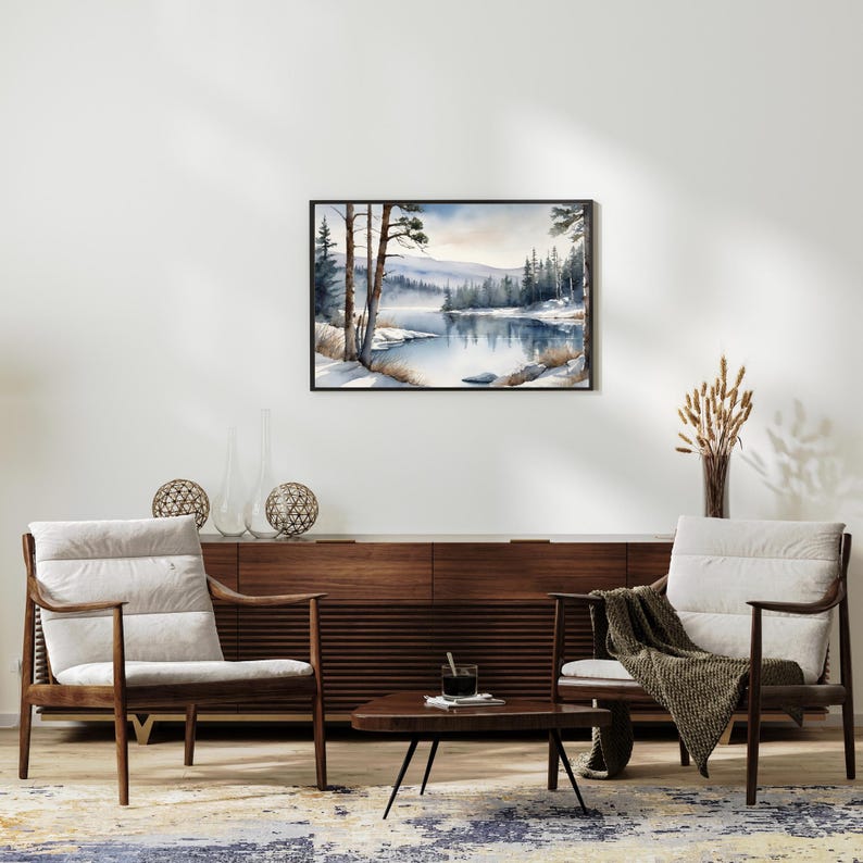 May include: A watercolor painting of a winter scene with a lake and trees. The lake is frozen and covered in snow. The trees are bare and covered in snow. The sky is a light blue color. The painting is framed in a black frame.