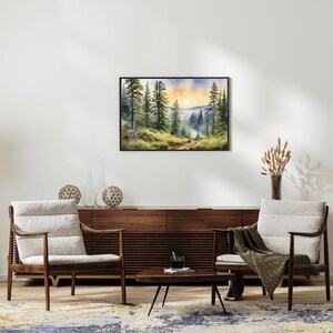Op de afbeelding: Een aquarel schilderij van een bos sc&egrave;ne met hoge bomen en een pad dat de diepte in loopt. De lucht is zacht blauw met hints van oranje en geel, wat suggereert dat het zonsopgang of zonsondergang is. Het schilderij is ingelijst in een zwart frame en hangt aan een witte muur.