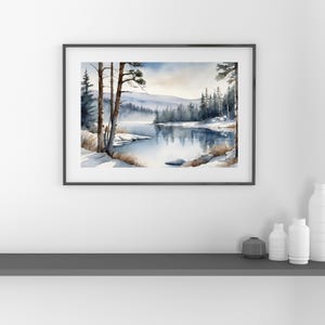 May include: A watercolor painting of a winter scene with a lake surrounded by snow-covered trees. The lake is reflecting the sky and the trees. The painting is framed in a black frame.