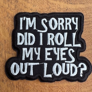 May include: Black embroidered patch featuring the text "I'M SORRY DID I ROLL MY EYES OUT LOUD?" in white, bold lettering. The patch has a black border and is designed for application to fabric items, such as jackets or bags.