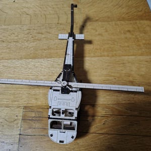 Puede incluir: Un modelo de madera de un helicóptero negro con un interior detallado y una hélice giratoria.