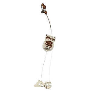 May include: A white owl-shaped wind chime with brown detailing, hanging from a thin metal chain. The owl has large eyes and a detailed chest. Two small, light-colored bear-shaped ornaments dangle below. Wooden beads and a small bird ornament are at the top.