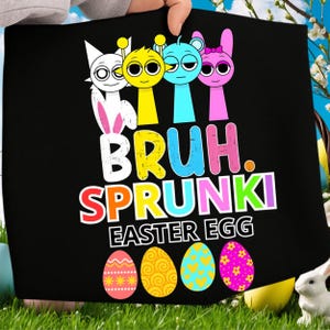 Puede incluir: Camiseta negra con el texto "BRUH. SPRUNKI EASTER EGG" y personajes de dibujos animados en amarillo, azul y rosa. El diseño incluye cuatro huevos de Pascua decorados en rosa, amarillo y azul.