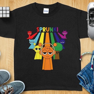 Peut inclure: T-shirt noir avec un motif arc-en-ciel et le texte "SPRUNKI" en blanc. Le motif présente un groupe de personnages de dessins animés avec des accents colorés.