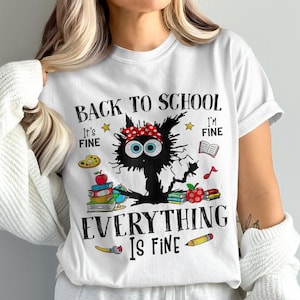 May include: White t-shirt with a black cat graphic wearing a red bandana, surrounded by school-themed illustrations and text that reads "Back to School Everything is Fine".