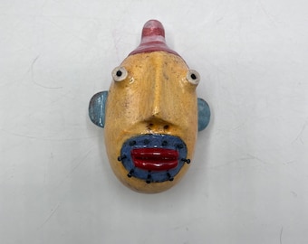 small round wall sculpture - yellow person w/blue nail beard