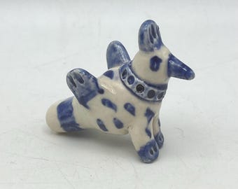 Escultura de arcilla con forma de silbato: un pequeño pájaro de color cobalto.