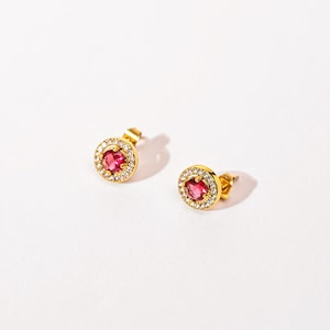 Peut inclure: Une paire de boucles d'oreilles clous en or avec une pierre précieuse rose entourée d'un halo de petites pierres précieuses claires.