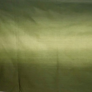 May include: A close-up of a fabric with a gradient of green hues. The color transitions from a darker olive green at the bottom to a lighter, almost yellow-green at the top. The fabric has a subtle sheen.