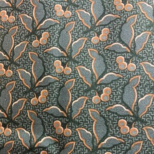 May include: Close-up of a fabric with a repeating pattern of stylized leaves and berries. The leaves are a muted blue-gray with orange outlines, and the berries are orange. The background is a dark teal with a subtle geometric design.