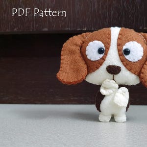 May include: A brown and white felt dog toy with big eyes and a brown nose. The toy is made in a simple style and is perfect for children to play with.