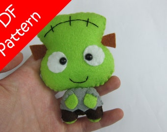 May include: A green felt Frankenstein monster plush toy with brown felt ears, white felt eyes, and black stitching. The monster is smiling and has a gray felt body.
