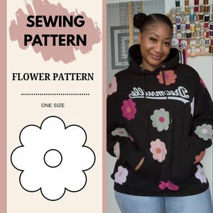 May include: A black hoodie with flower appliqués in pink, purple, and green. The hoodie has the word "Dreamer" in cursive script across the chest. The image also shows a sewing pattern for a flower design, with the text "Sewing Pattern" and "Flower Pattern".