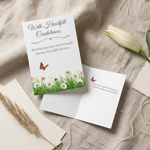 Puede incluir: Tarjeta de condolencia blanca con el texto "With Heartfelt Condolences" y "Sending you love and strength during this difficult time." La tarjeta presenta una mariposa y un diseño floral con margaritas y hierba verde.