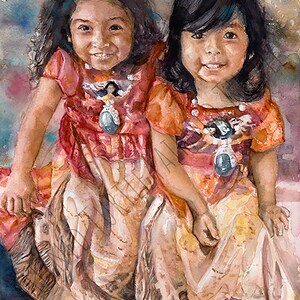 May include: Two young girls wearing traditional Native American clothing with intricate beadwork and turquoise accents. They are smiling and sitting together, with the girl in the front holding a small object in her hand.