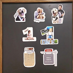 以下が含まれることがあります： 人やペットの写真が載った、パーソナライズされたマグネットのコレクションです。マグネットには、ミロという名前の犬、50周年記念を祝うカップル、サイモンという名前の赤ちゃん、バイオレットという名前の女の子、キッチンの換算表、エリカ・スミスさんの不動産看板があります。