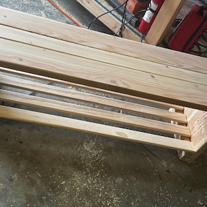 May include: A wooden bench with a shelf underneath. The bench is made of natural wood and has a rustic look.