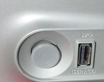 May include: A silver computer chassis panel featuring a circular power button, a USB port labeled SERVICE, a blue USB 3.0 port labeled PC, an additional USB port, a headphone jack, and a power input port, all arranged in a horizontal recessed row.