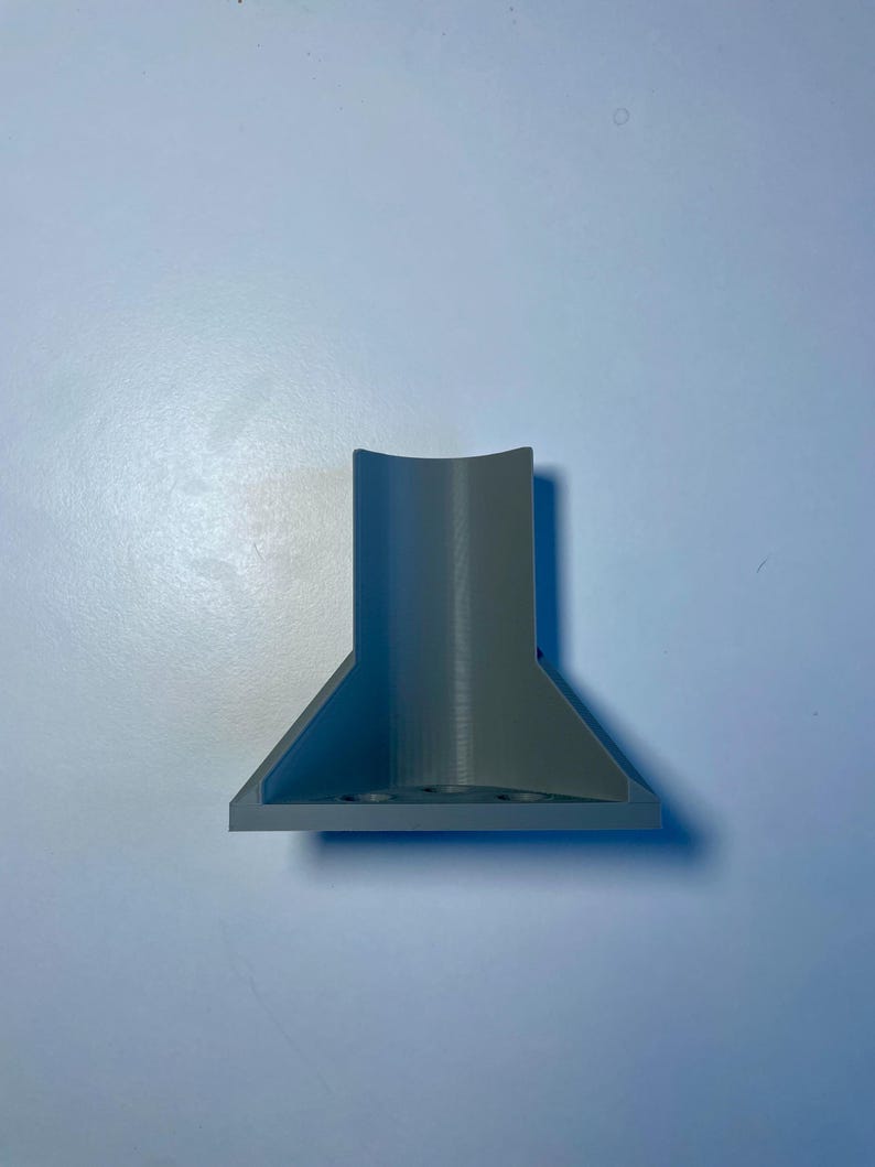 May include: A gray plastic 3D printed object with a cylindrical top and a triangular base.