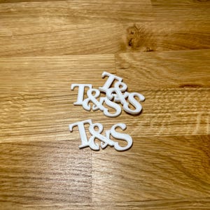 Drinks topper in white on a wooden desk. Initials T&S