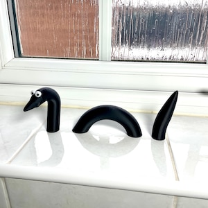 May include: A black, three-piece, segmented, plastic toy resembling a sea serpent with googly eyes.