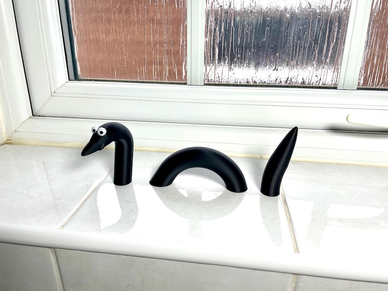May include: A black, three-piece, segmented, plastic toy resembling a sea serpent with googly eyes.