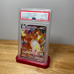 May include: A graded Pokemon trading card featuring Charizard VMAX from the Darkness Ablaze set. The card is in a protective case with a Gem Mint 10 rating and a PSA label.