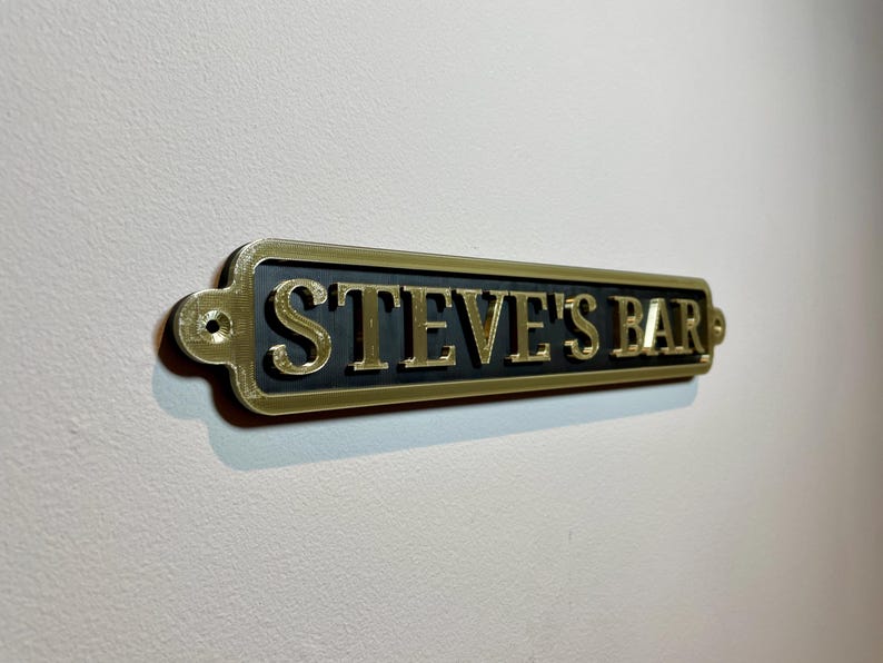 May include: A gold-colored metal sign with black lettering that reads "STEVE'S BAR".