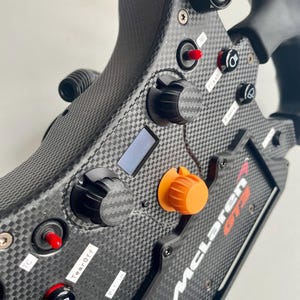 Radial dials on a fanatec mclaren GT3 V2 wheel. 2 black 1 orange with carbon fibre accent