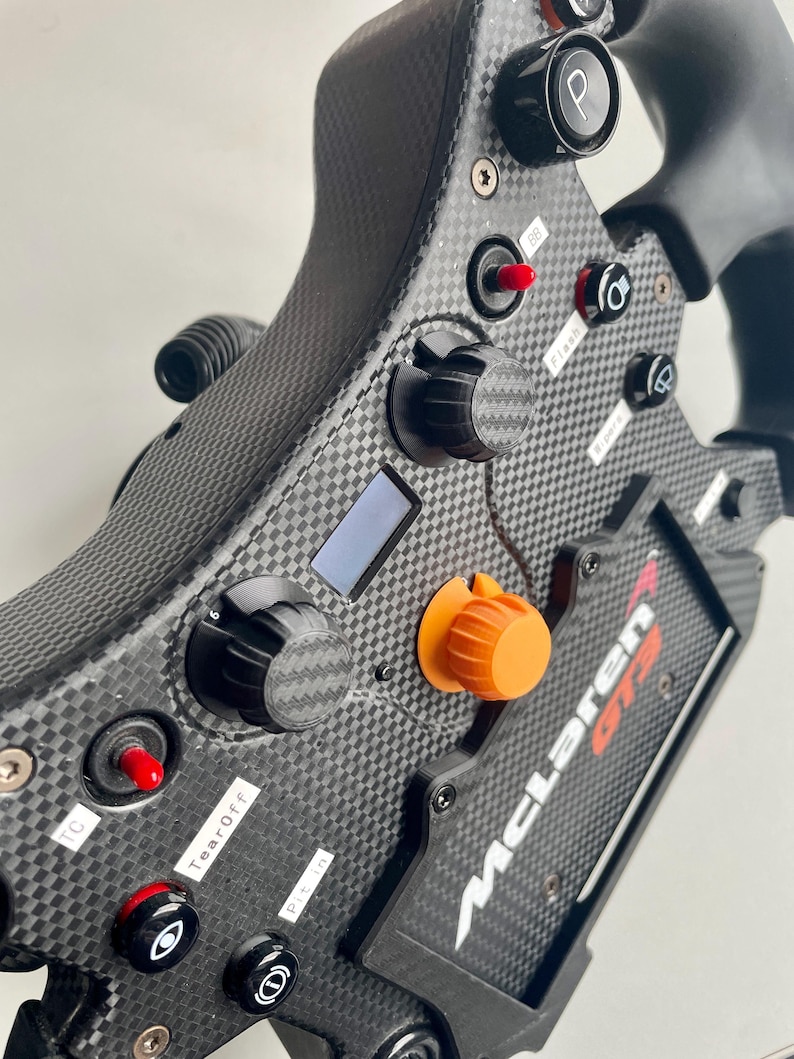 Radial dials on a fanatec mclaren GT3 V2 wheel. 2 black 1 orange with carbon fibre accent