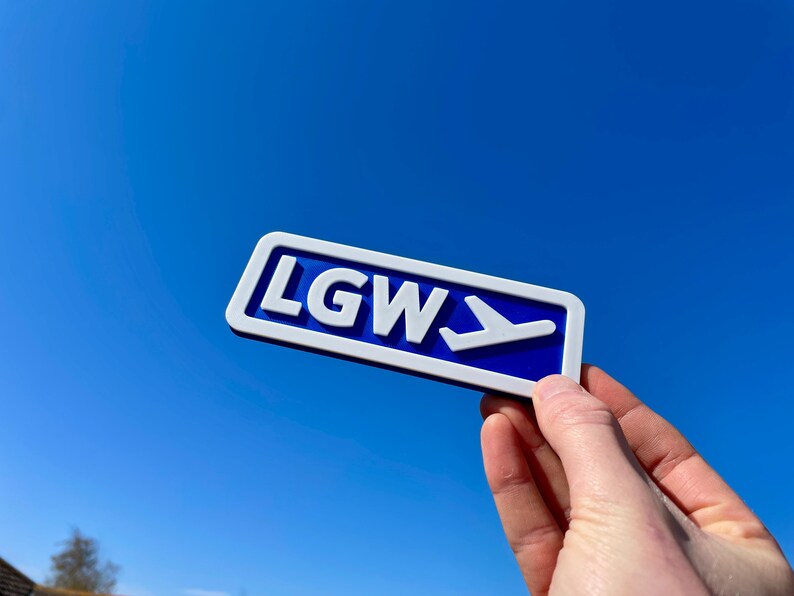 May include: A blue and white sign with the letters LGW and a white airplane symbol pointing to the right.