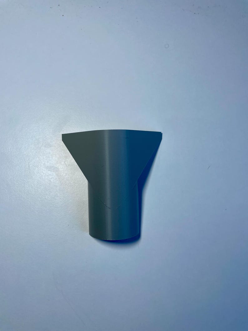 May include: A gray plastic nozzle with a wide opening at the top and a narrower opening at the bottom.