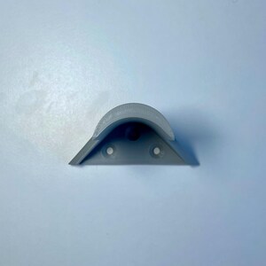 May include: A gray plastic corner shelf bracket with three holes for mounting.