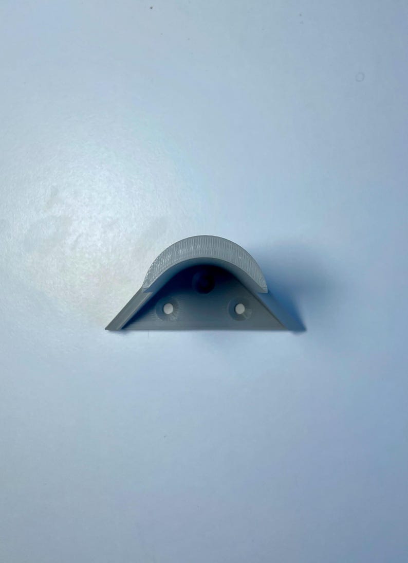 May include: A gray plastic corner shelf bracket with three holes for mounting.