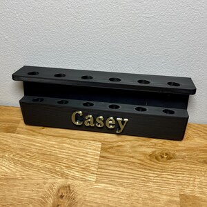 Wall mounted dart holder. Black with Bronze personalised text on the front reading Casey