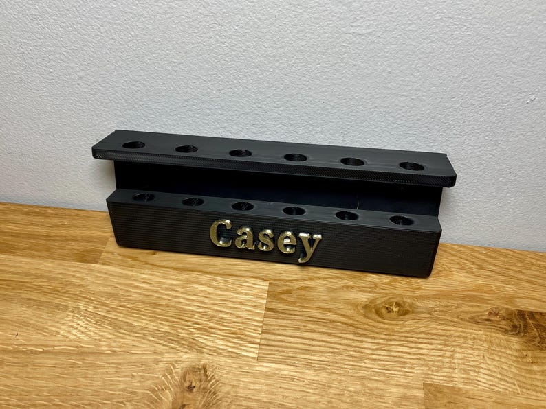 Wall mounted dart holder. Black with Bronze personalised text on the front reading Casey